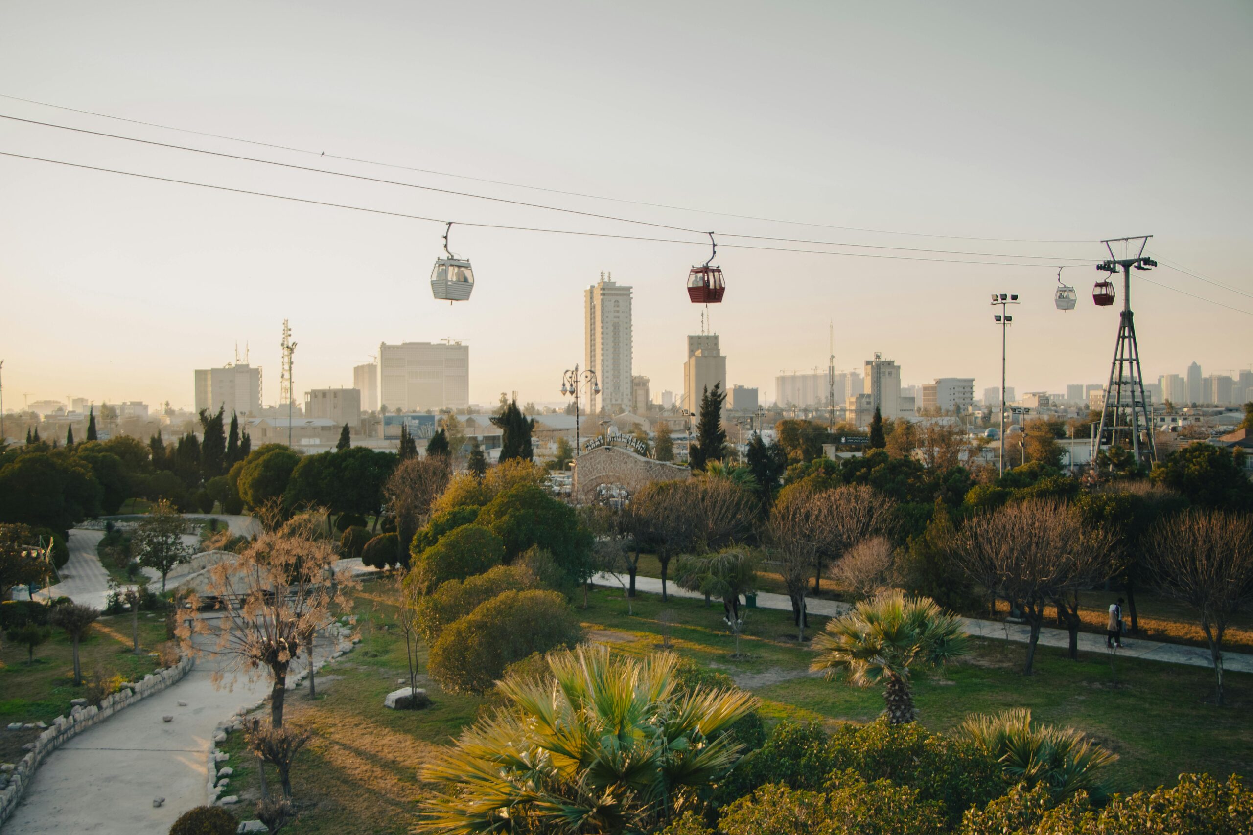 Panoramic view of Erbil cityscape with cable cars and park at sunset.