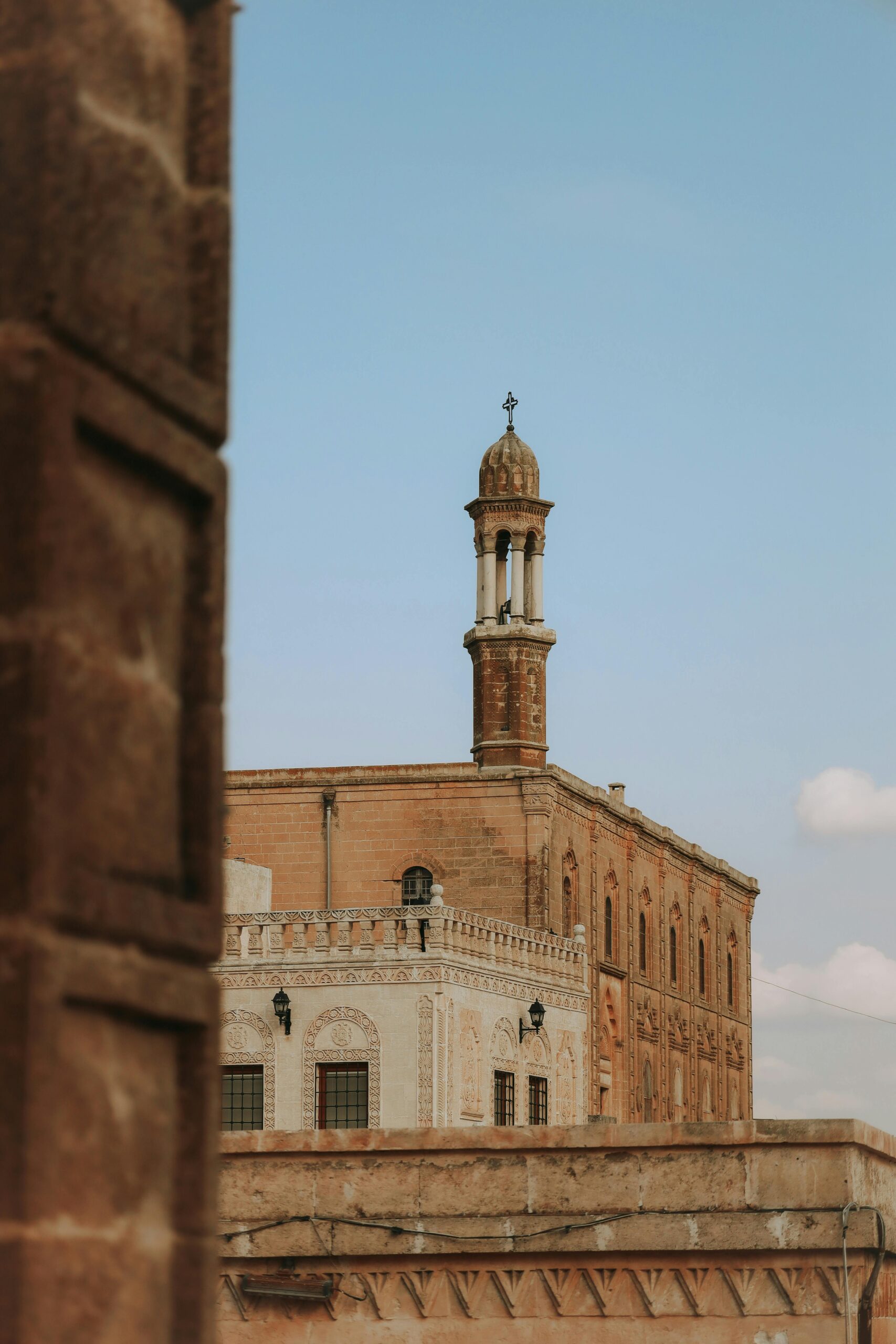 A serene view of a historic mosque with a prominent minaret against a clear blue sky.
